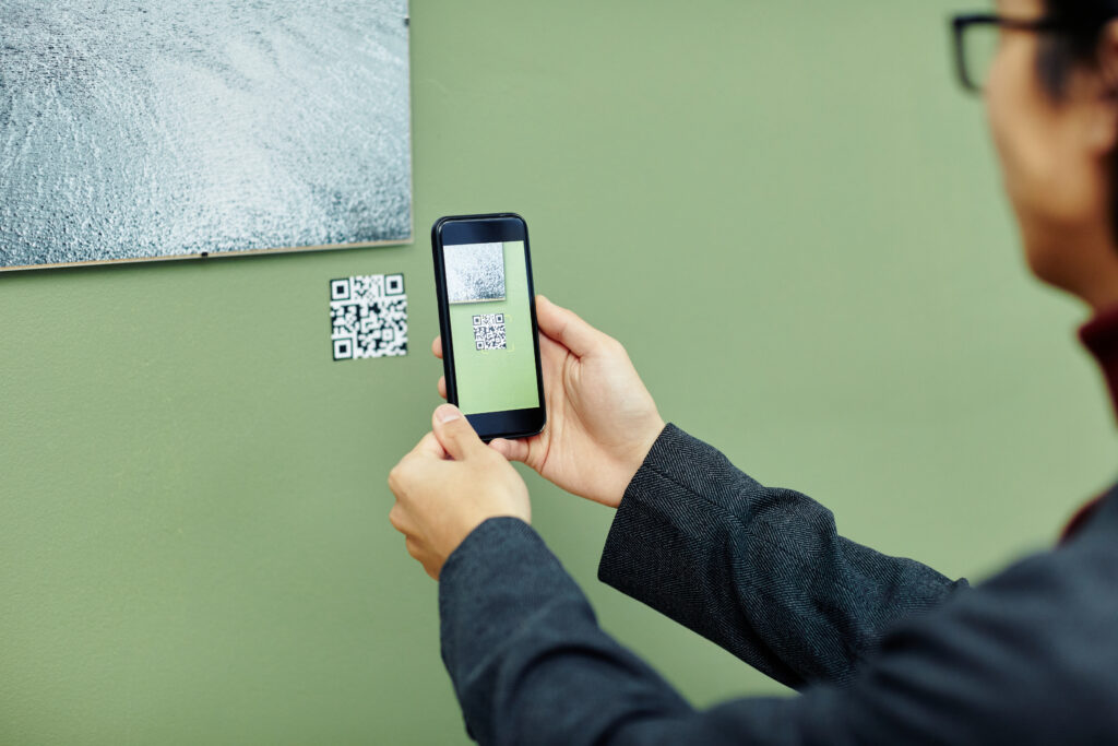 Persoon scant een QR code onder een schilderij.