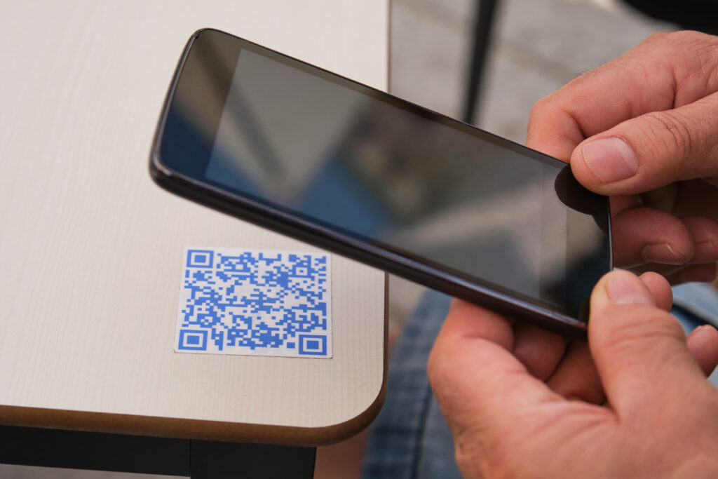 Persoon scant een QR code op een tafel met telefoon.